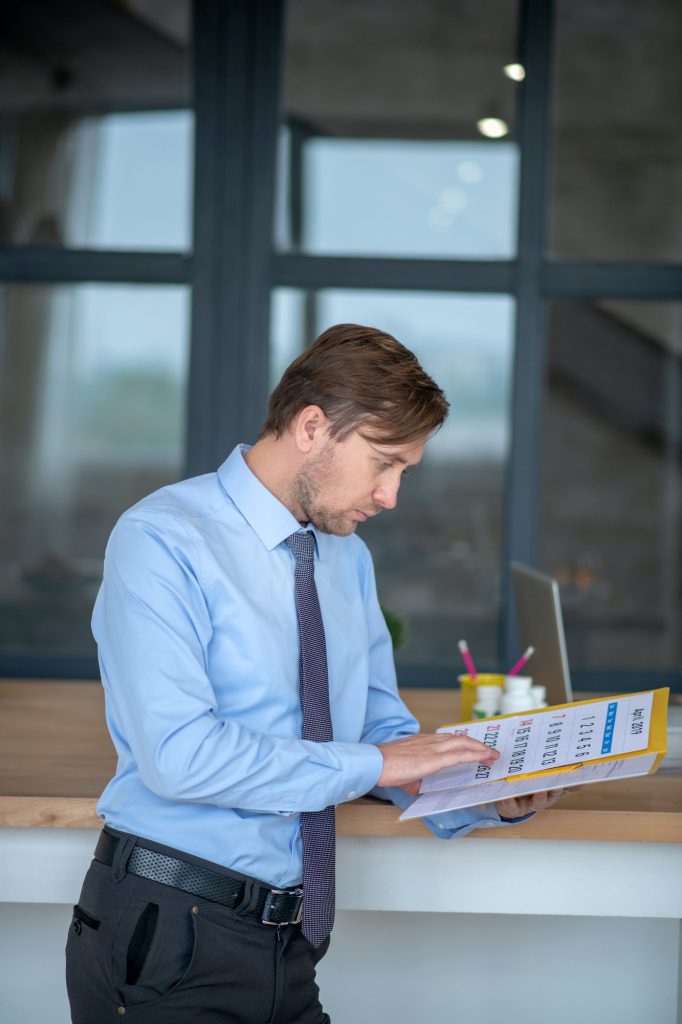 Dark-haired young handsome businessman checking the calendar